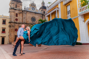 Flying Dress Cartagena® Old City couple photoshoot featuring teal gown and historic Cartagena backdrop.