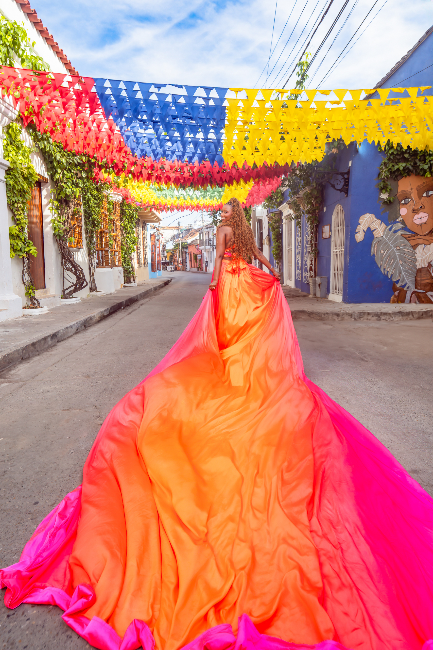Orange and pink flying dress photoshoot under colorful flags in Getsemaní Cartagena
