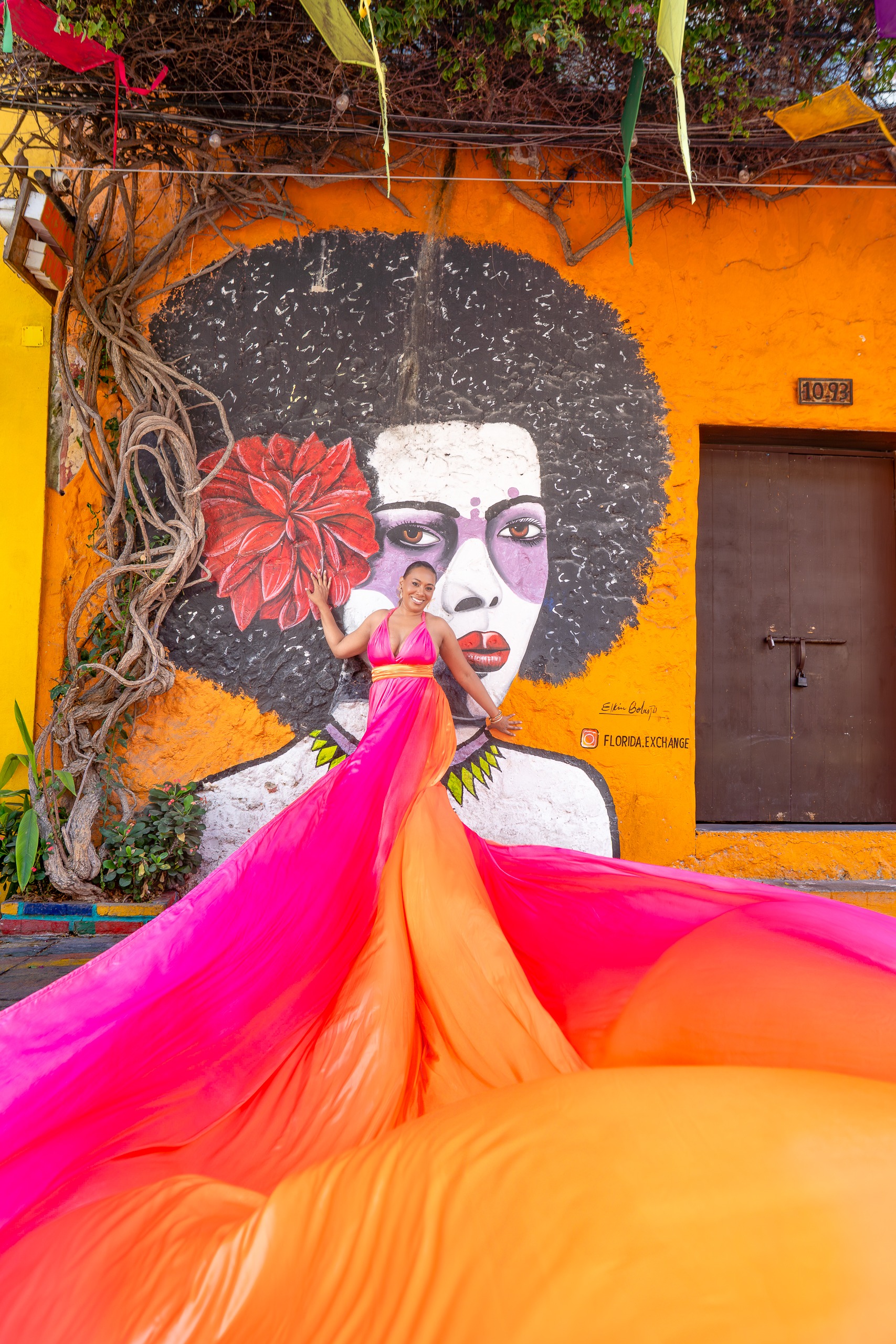 Pink and orange flying dress photoshoot in front of a mural in Getsemaní Cartagena